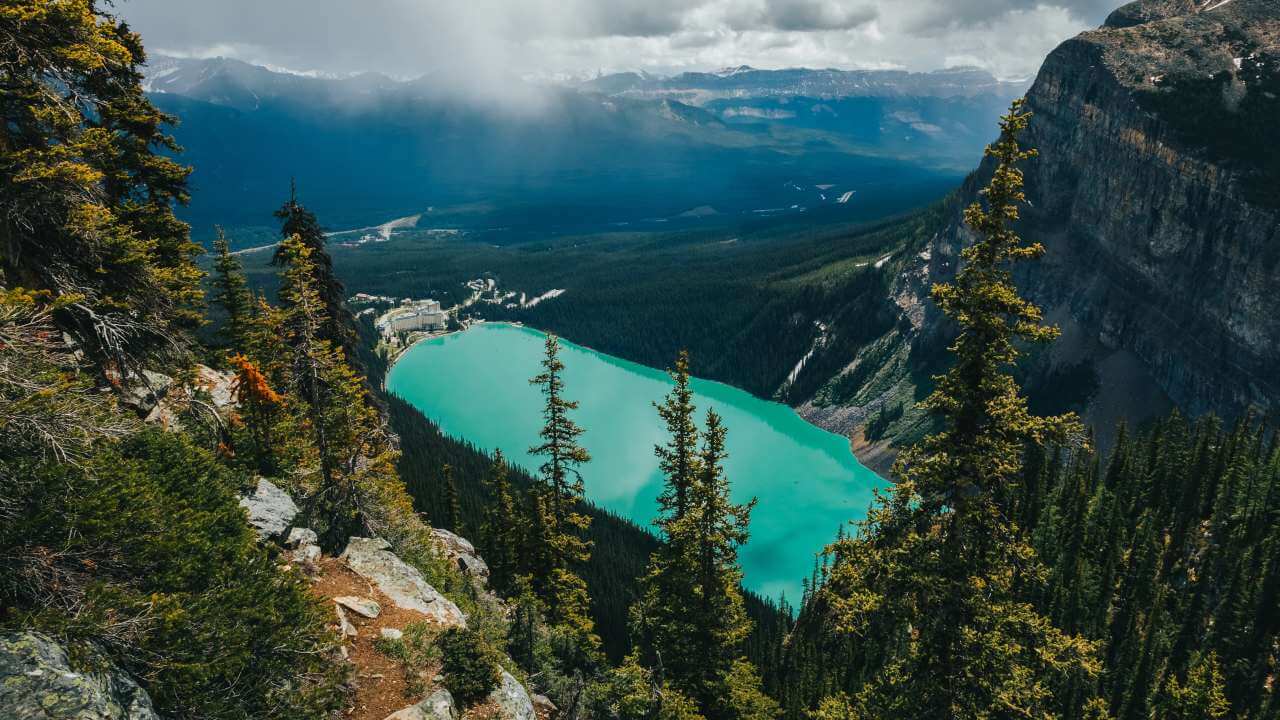 high above bee hive trail looking down onto lake louise and hotel with mountain range view in background